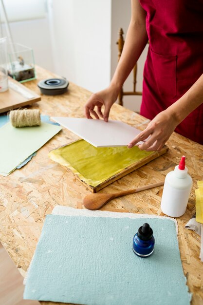 木製の机の上に手作りの紙を準備する女性