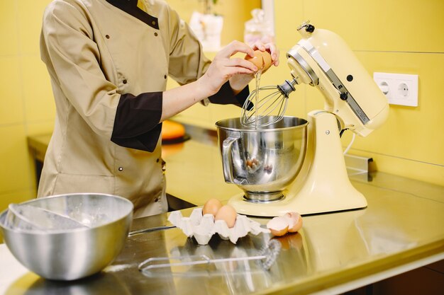 Woman preparing pastries. Confectioner in a coat.