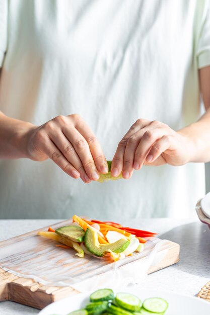 Free photo woman preparing spring rolls in rice paper on kitchen table