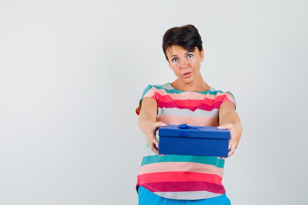 Женщина представляет подарочную коробку в полосатой футболке