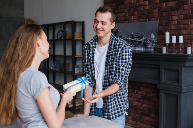 Woman presenting gift to man at home 