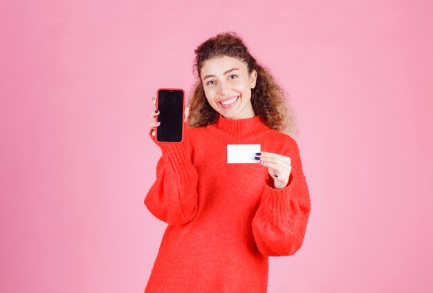 woman presenting her business card and showing her phone by meaning to get in touch.