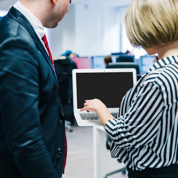 Woman presenting laptop to man in office