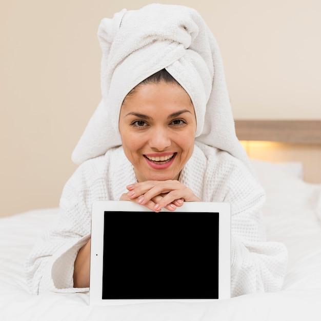 Foto gratuita donna che presenta tablet nella camera d'albergo