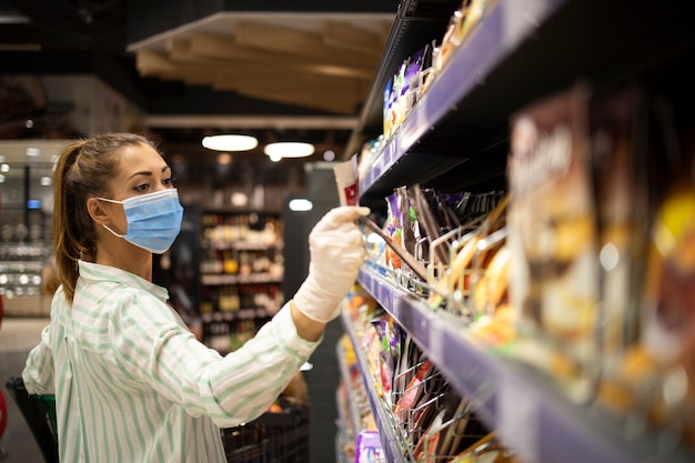 スーパーマーケットで買い物をしながらコロナウイルスから身を守る女性