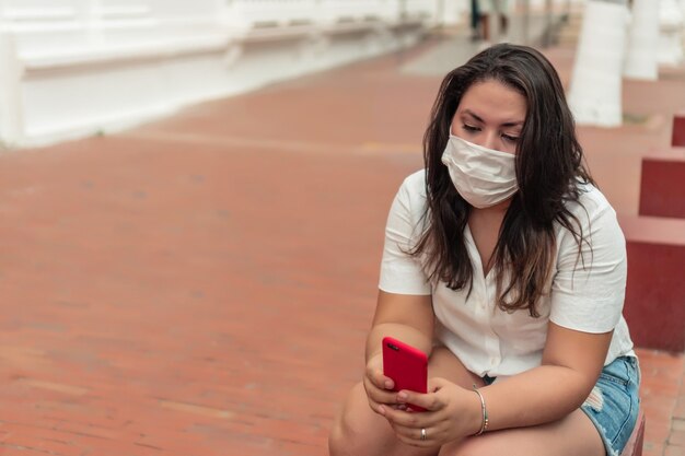Woman in protective mask in the city checking her cell phone