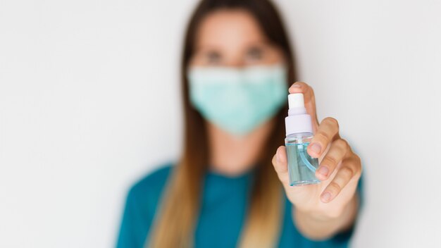 Woman in protective mask  washing hands with hand sanitizer