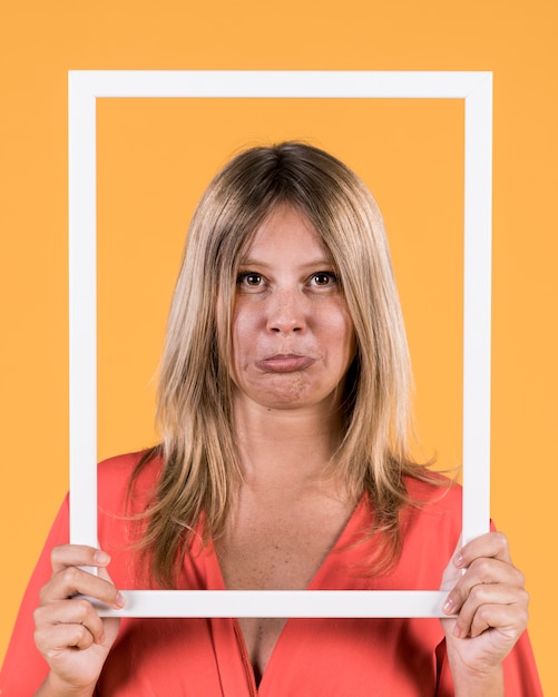 Woman puckering lips while holding white border picture frame front of her face