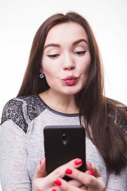 Woman puckering lips while taking picture with cellular phone