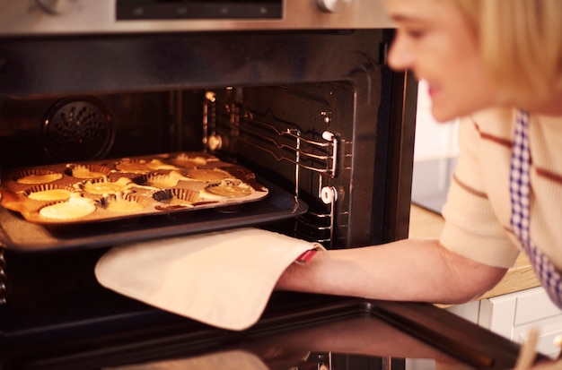 Woman pulls muffins from the oven