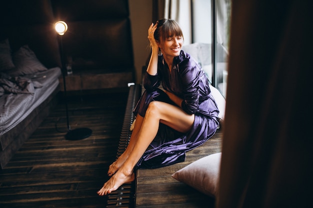 Woman in purple bathrobe in bedroom