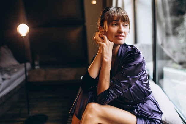 Woman in purple bathrobe in bedroom