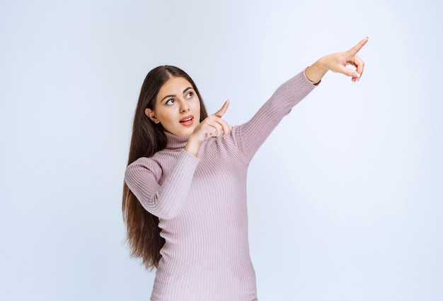 Free photo woman in purple shirt showing something above.