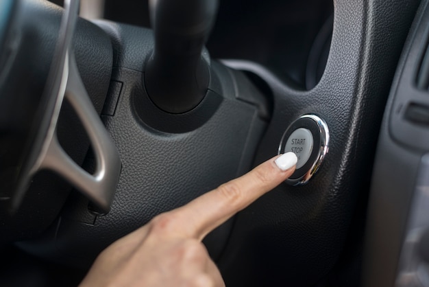 Woman pushing the start button from the car