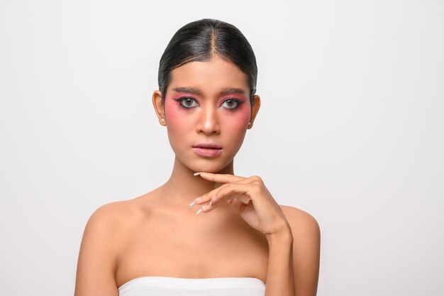 Woman put on pink makeup and put her hand on her chin isolated on white