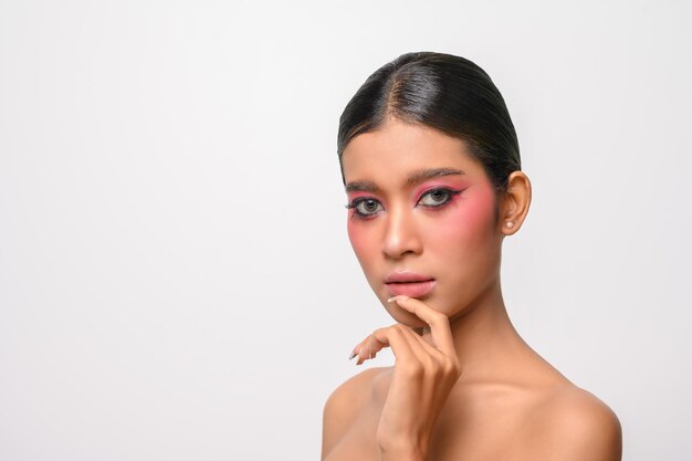 Woman put on pink makeup and put her hand on her chin isolated on white