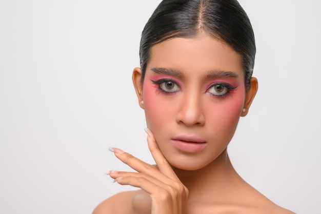 Woman put on pink makeup and put her hand on her face isolated on white