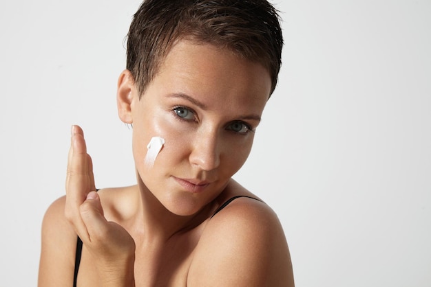 Woman puts cream on a cheek