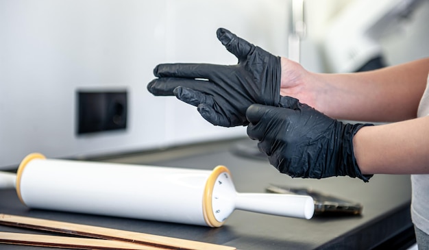 Free photo a woman puts on gloves in the kitchen kitchen work and hygiene