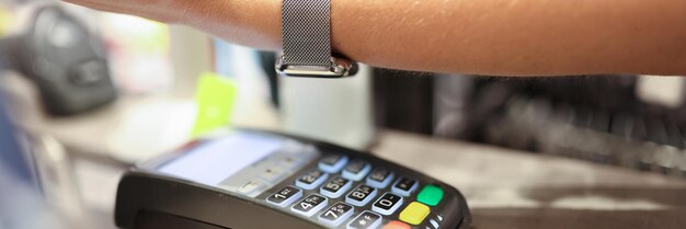 Woman puts hand with smart watch and pays contactless payment secure payment by bank terminal