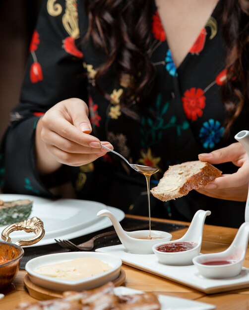 woman puts honey on her bread in traditional breakfast setup