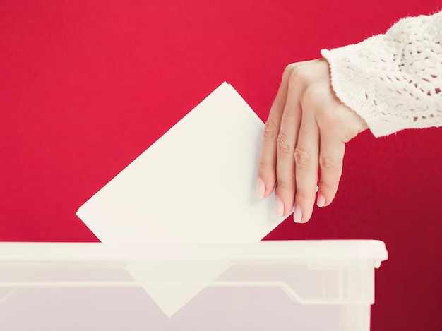 Женщина кладет макет карты в коробку для выборов