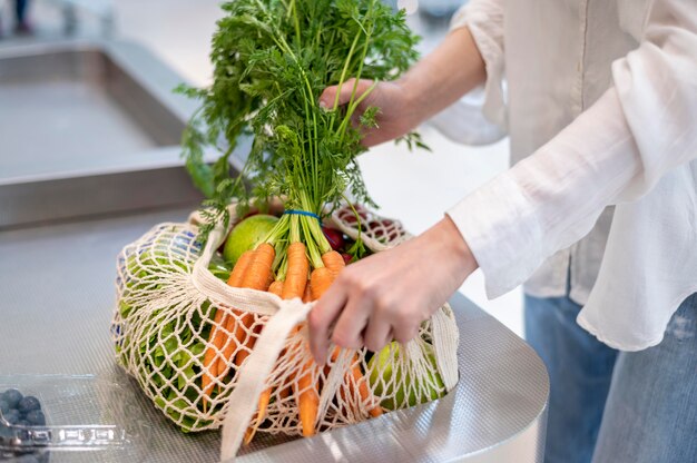 Женщина кладет продукты в сумку многоразового использования