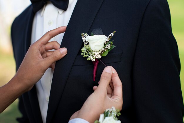 Женщина надевает цветок на костюм своего парня на выпускной