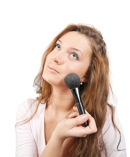 woman putting make up on her face with a brush