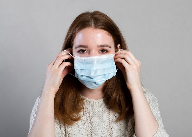 Женщина надевает медицинскую маску для защиты