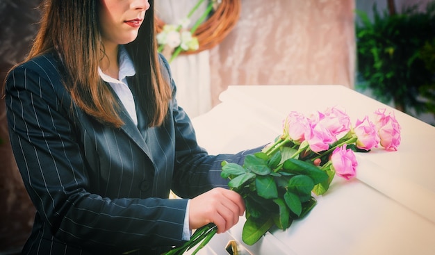 Woman putting rose on coffin at funeral