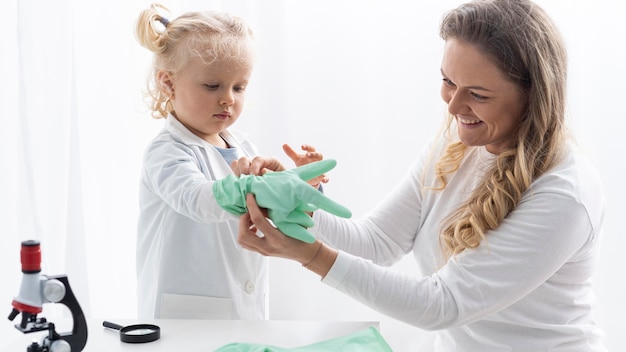 Woman putting safety gloves on toddler before learning about science