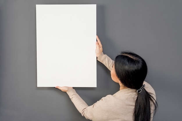 Free photo woman putting on wall balnk paper sheet