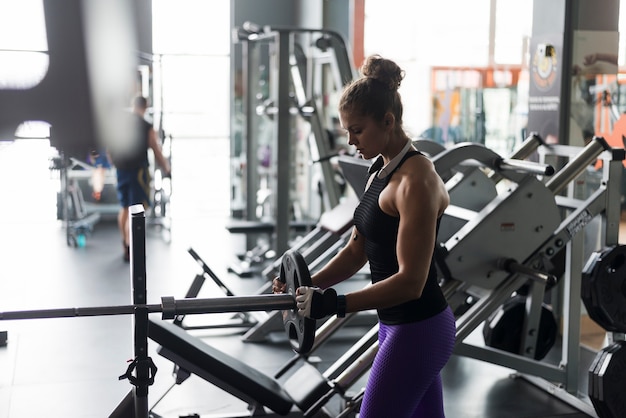 Woman putting weight on barbell