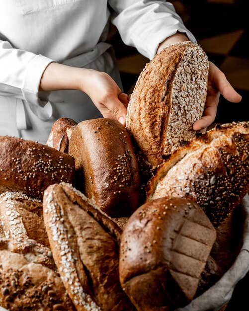 Женщина кладет булочку цельнозерновой хлеб среди других хлебов
