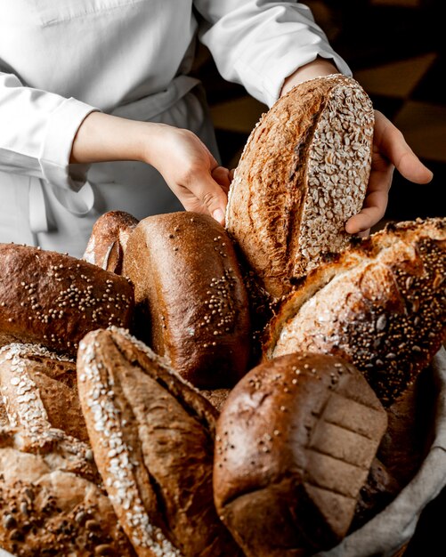 Woman putting whole grain bread bun among other breads