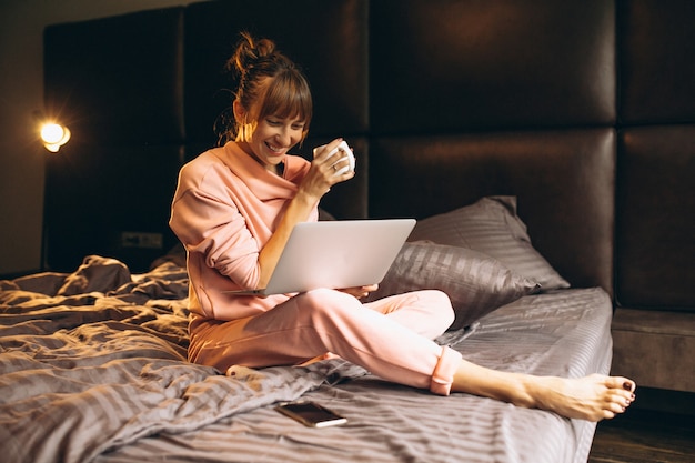 Woman in pygama working on laptop in bed