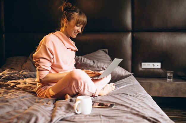 Woman in pygama working on laptop in bed