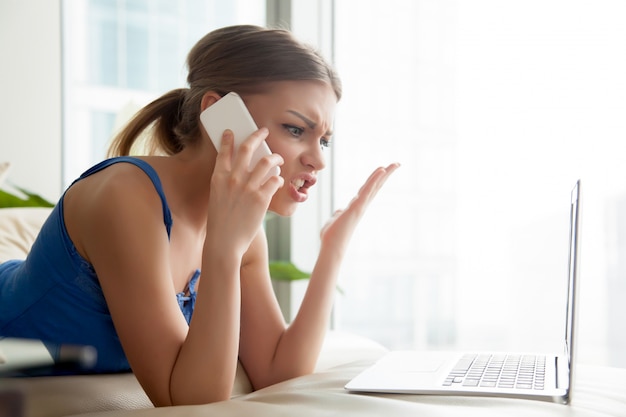 Woman quarreling on cellphone while using laptop