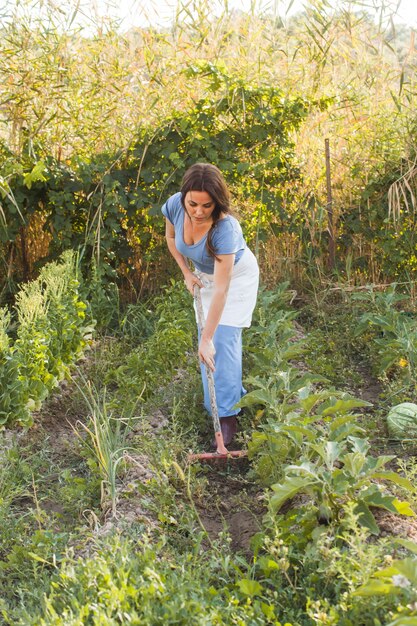 Женщина ломает почву в поле