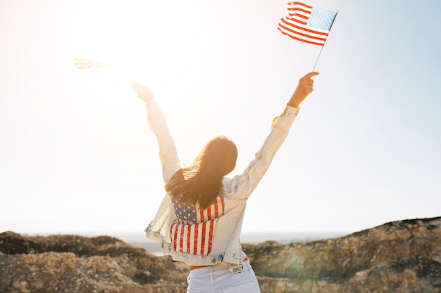 Woman raising hands with flags on mountain