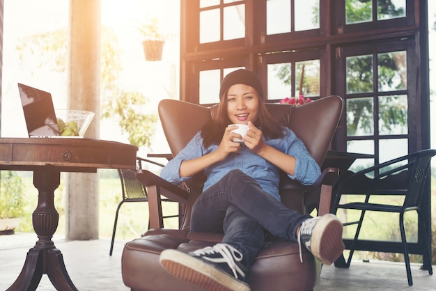 Woman raising with a coffee cup,smiles lying on the couch, sofa.