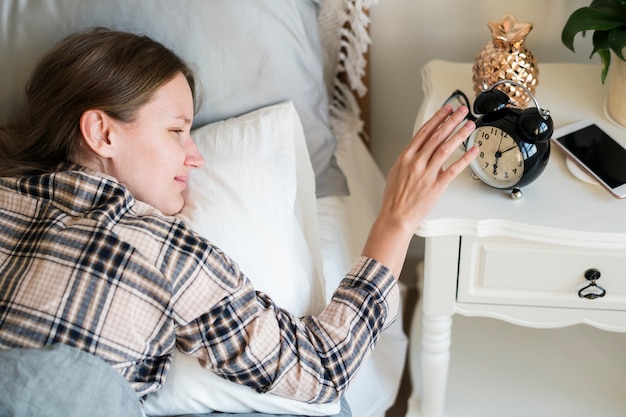 Free photo woman reaching hand to turn off the alarm