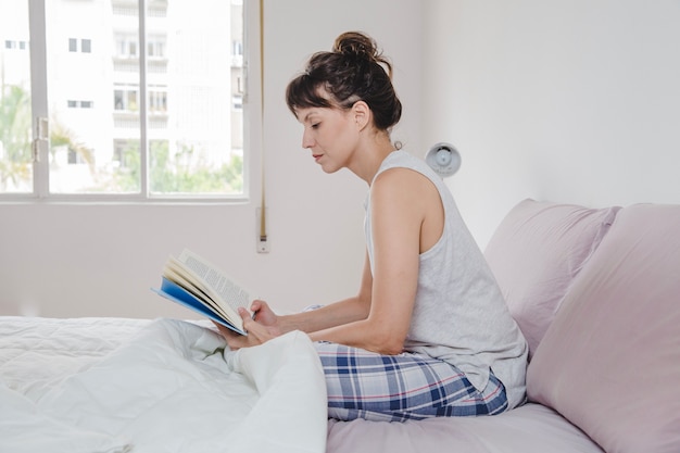 Женщина читает в постели