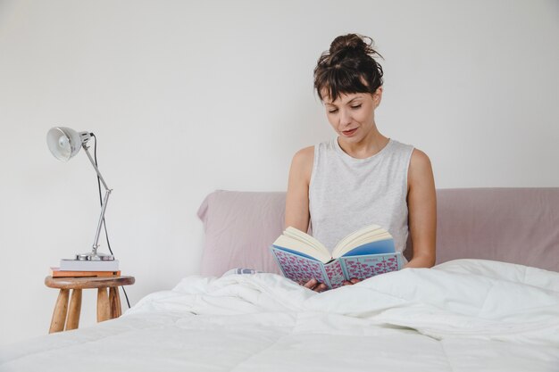 ベッドで読書する女性