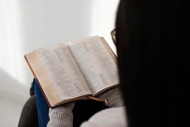 Foto gratuita donna che legge la bibbia al chiuso