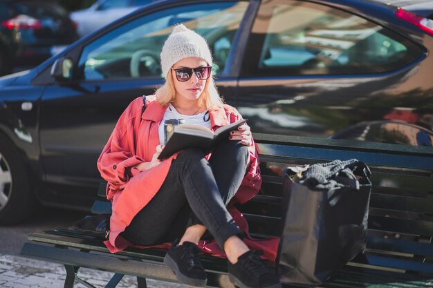 woman reading book on bench