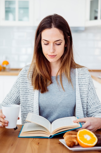 Woman reading book during breakfast