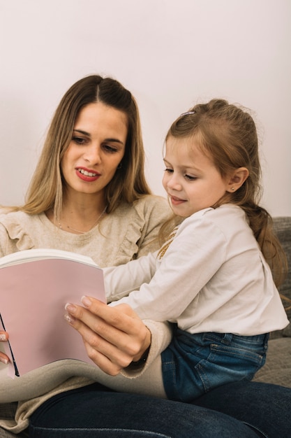 Woman reading book to cute daughter