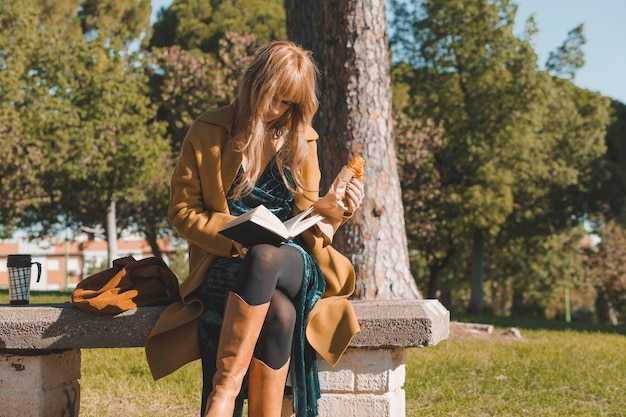 Женщина читает книгу и едят круассан